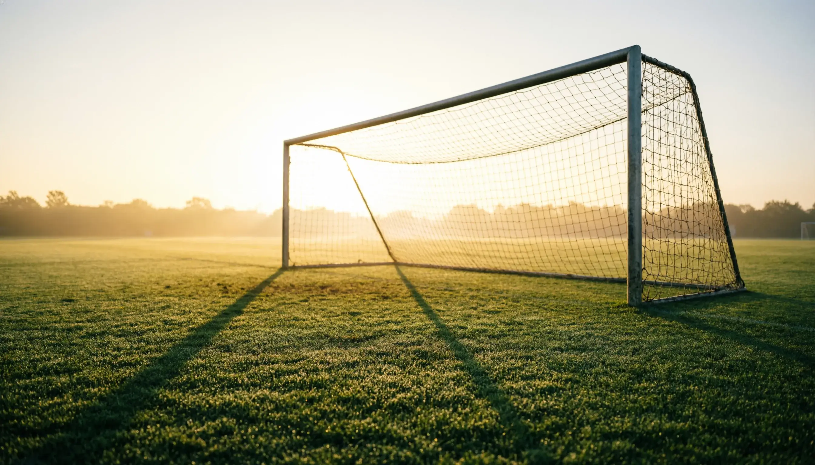 Sonnenaufgang über einem Fussballfeld als Symbol für langfristigen Erfolg